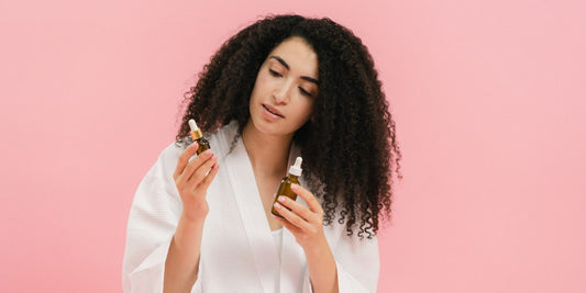 A woman holding bottles of argan oil for hair.
